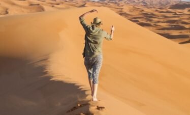A man walking across a sandy dune in the desert