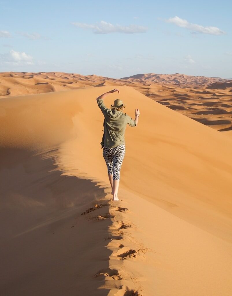 A man walking across a sandy dune in the desert
