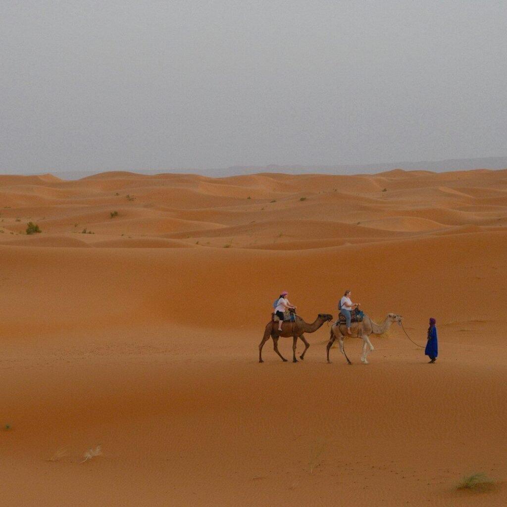 Two people riding camels in a vast desert landscape.