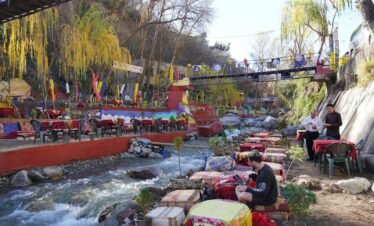 a group of people sitting at a table next to a river