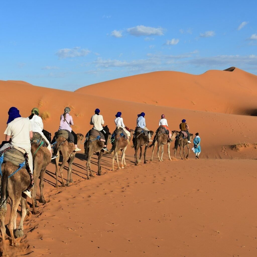 a group of people riding camels in the desert