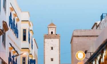 a group of people walking down a street next to tall buildings